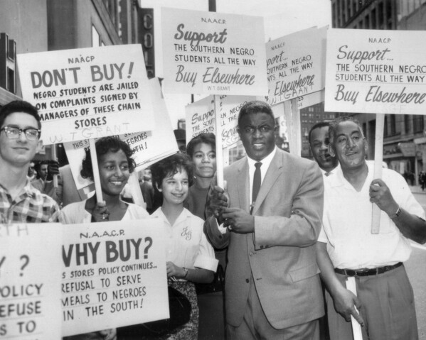 Former baseball star Jackie Robinson holds a sign as he joins a picket line in Cleveland in 1960, to protest discrimination against Blacks at southern lunch counters. (AP Photo/File)